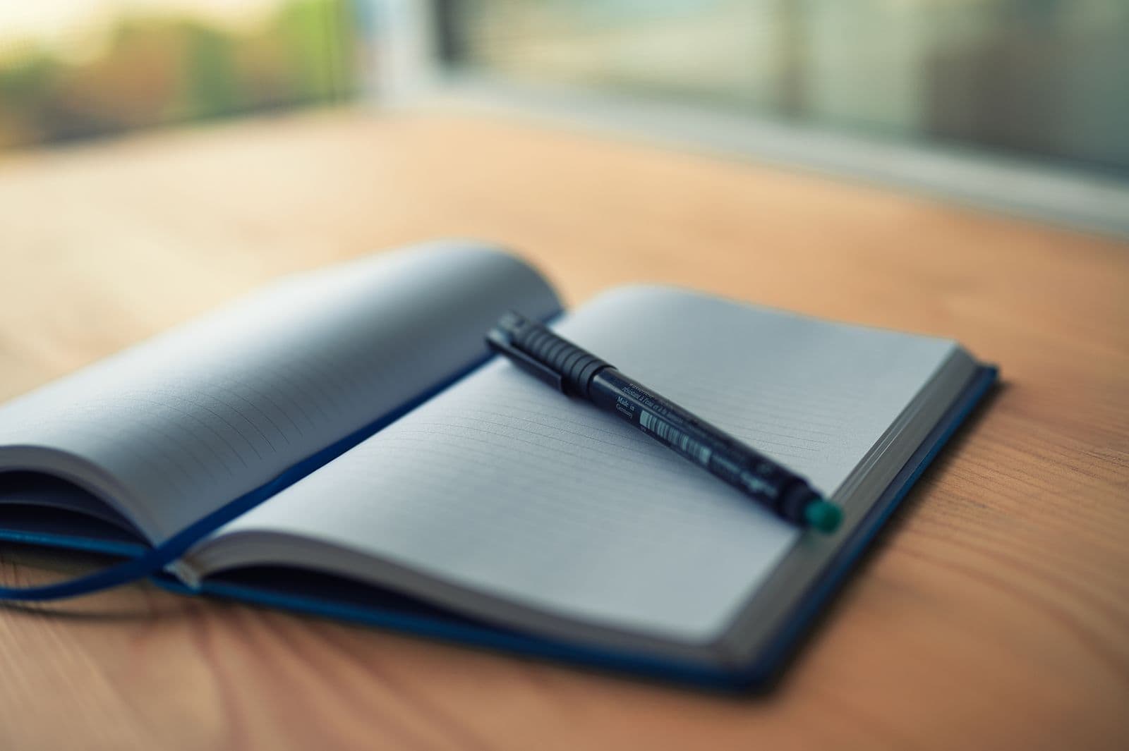 An open lined notebook with a pen on a wooden desk